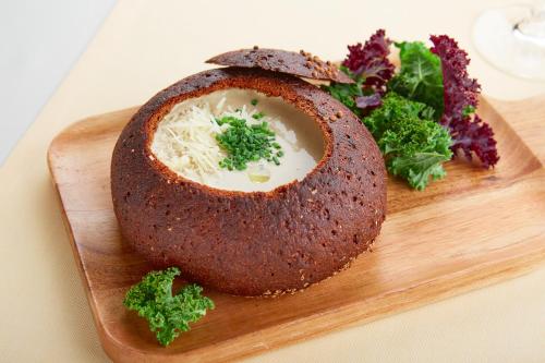 a piece of bread with cheese and greens on a cutting board at Park Hotel Latgola in Daugavpils