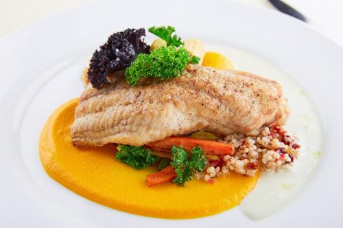 a plate of food with a piece of fish and vegetables at Park Hotel Latgola in Daugavpils