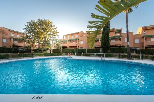 una grande piscina blu di fronte ad alcuni edifici di Apartamento Mijares a Chiclana de la Frontera