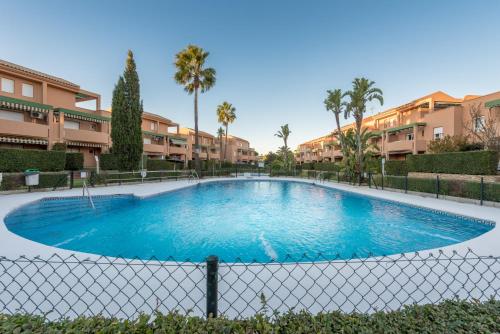 Una gran piscina con palmeras y edificios. en Apartamento Mijares, en Chiclana de la Frontera