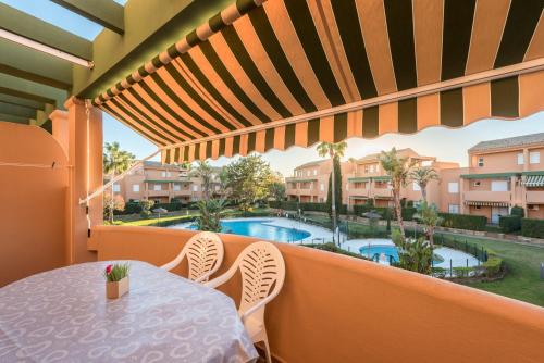 un balcone con tavolo, sedie e piscina di Apartamento Mijares a Chiclana de la Frontera