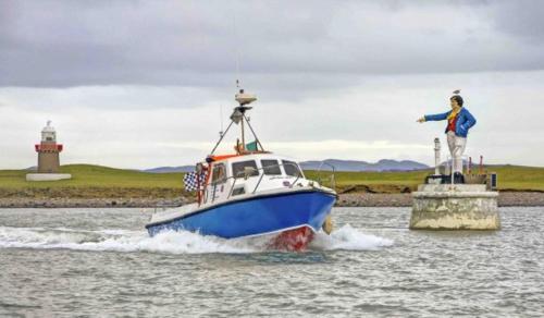 a blue and white boat in the water with a statue at Old Fort Lodge in Sligo
