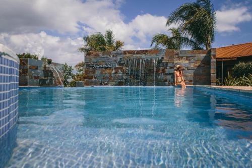 una mujer parada en una piscina en un resort en La Guarida Hotel & Spa en Capilla del Monte