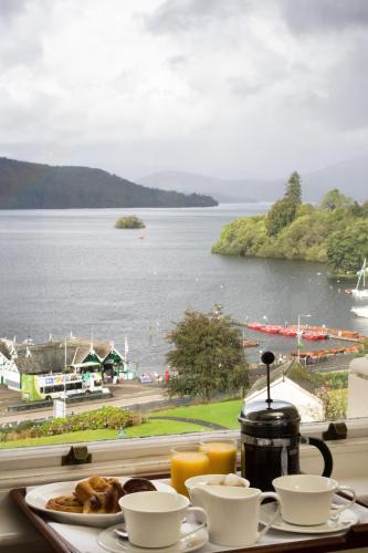 een dienblad met eten en uitzicht op het water bij The Belsfield Hotel in Bowness-on-Windermere