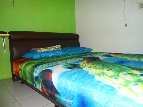 a bed with a colorful blanket and pillows on it at Bule Homestay Cianjur in Tjiandjur