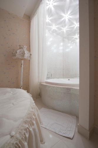 a white bathroom with a tub and a window at Deluxe Hotel Kupava in Lviv