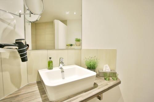 ein Badezimmer mit einem weißen Waschbecken und einem Spiegel in der Unterkunft Bergers-Landgasthof in Enge-Sande