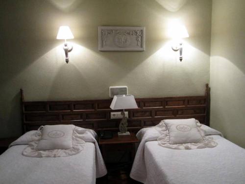 two beds in a room with two lamps on the wall at Hotel Boutique Balaitus in Sallent de Gállego