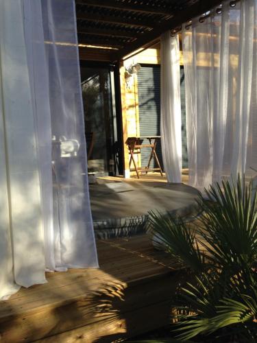 - une terrasse couverte avec des rideaux blancs dans une maison dans l'établissement L'Haute en couleur cabanes spas, à Audenge