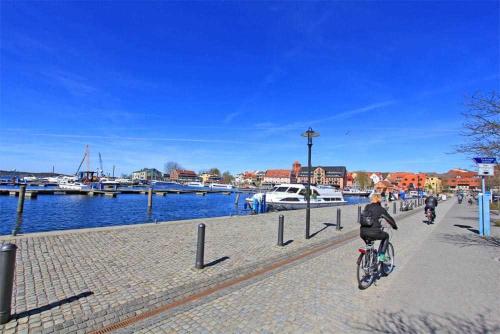 ヴァーレンにあるFerienhaus Waren SEE 7101の川沿いの歩道を自転車に乗る女
