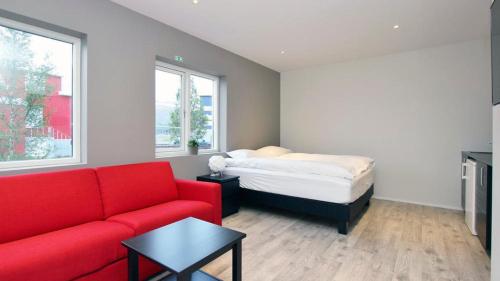 a living room with a red couch and a bed at Lava Apartments & Rooms in Akureyri