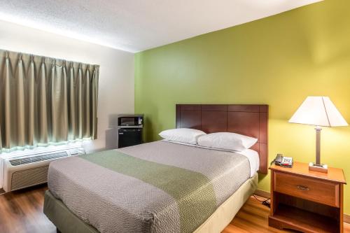 a bedroom with a bed and a lamp and a window at Motel 6-Petersburg, VA - Fort Lee in Petersburg