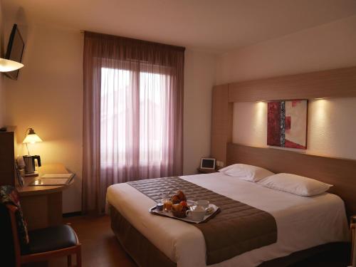 a hotel room with a bed with a tray of food on it at Cévenol Hôtel in Millau