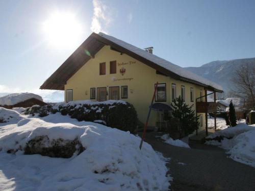 a house covered in snow with the sun behind it at Landhaus Tirol in Presseggersee