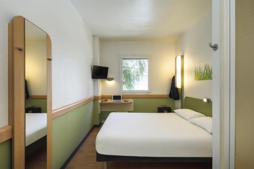 マラガにあるイビス バジェット マラガ セントロの白いベッドと窓が備わる客室です。