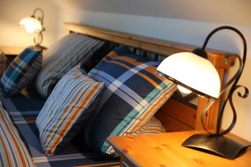 a bed with pillows and a lamp on a table at Penzion Recall in Troskovice