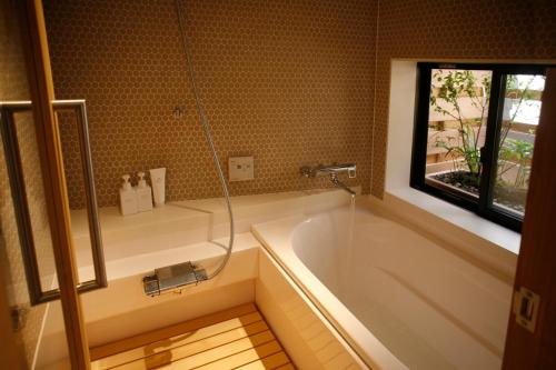 Un baño con bañera y ventana. en HANARé Gion, en Kioto