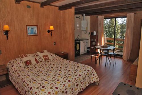 a bedroom with a bed and a table and a kitchen at Cabañas Vasconia in Castro