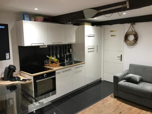 une cuisine avec des armoires blanches et un canapé dans une pièce dans l'établissement la petite barque, à Menton