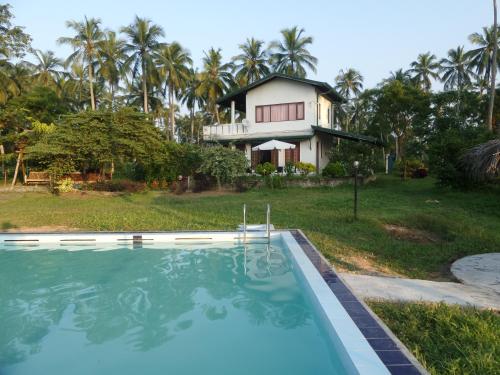 une maison avec une piscine en face d'une maison dans l'établissement cocoworld bungalow, à Bandara Koswatta
