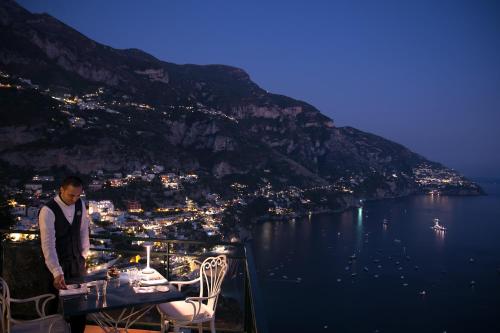 a man standing on top of a table with a view of a city at Hotel Le Agavi in Positano