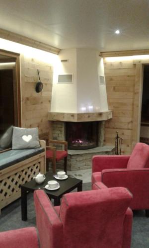 a living room with red chairs and a fireplace at Hôtel Flor'Alpes in La Giettaz