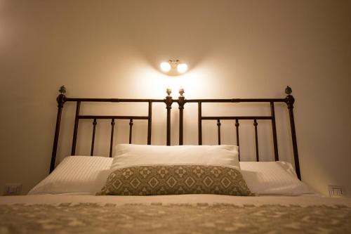 a bed with a headboard with a light on the wall at Ai Sottani B&B Deluxe Suite in Gioia del Colle