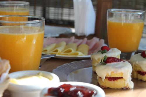 a table topped with plates of food and orange juice at Vila Tamú in Praia do Rosa