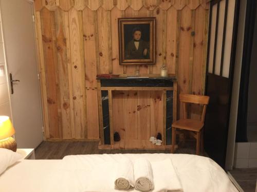 ein Schlafzimmer mit einem Bett und einem Bild eines Mannes in der Unterkunft Hôtel Le Caillebotis in Cap-Ferret