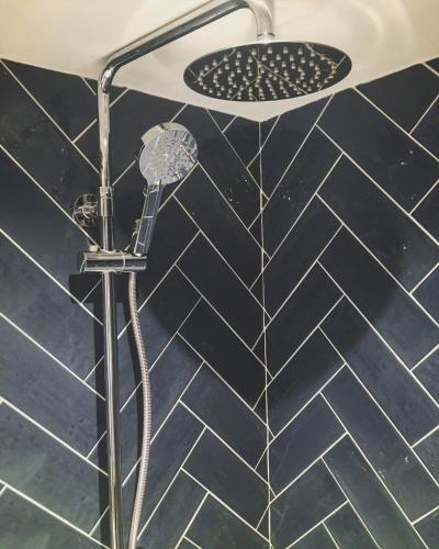 a shower in a bathroom with black and white tiles at The Side, Gower - Cosy, Coastal, Sea Views & Hot Tub in Horton