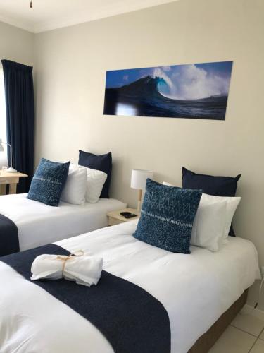 a bedroom with two beds with blue and white pillows at 10 on Beresford in East London