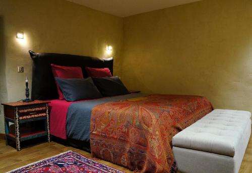 a bedroom with a large bed and a stool at Domaine des Maréquiers chambre Pimprenelle in Saint-Germain-du-Teil