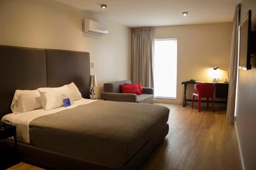 a hotel room with a bed and a living room at Regency Way Montevideo Hotel in Montevideo