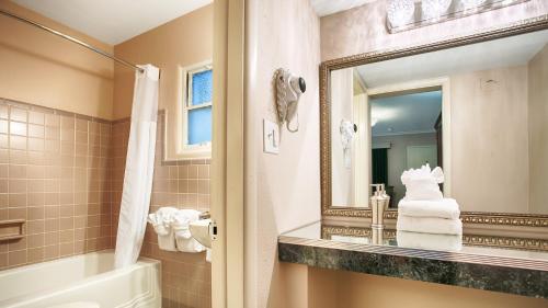 a bathroom with a tub and a sink and a mirror at Best Western Route 66 Rail Haven in Springfield