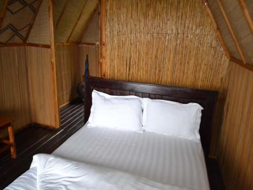 1 dormitorio con 1 cama con sábanas y almohadas blancas en Rwiza Village, en Gitesi