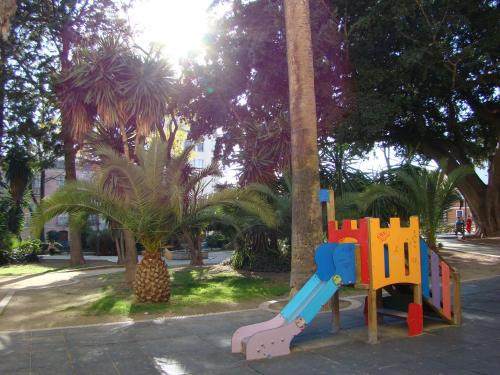 a playground with a slide in a park with palm trees at Málaga Lodge Guesthouse in Málaga
