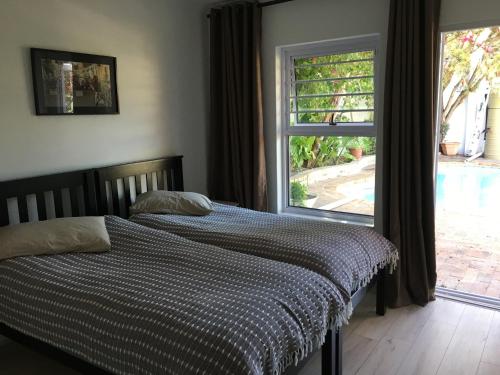 1 cama con manta a cuadros frente a una ventana en Sunbird en Hout Bay