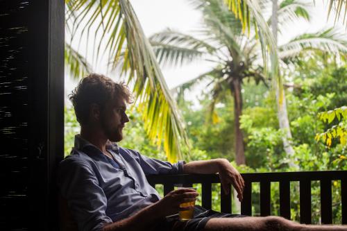 a man sitting on a bench holding a beer at KAJU GREEN eco lodges in Unawatuna