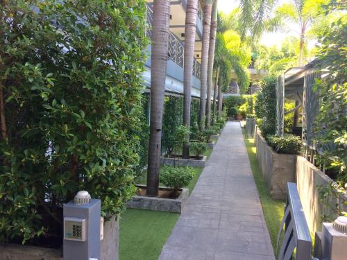 a walkway through a garden with palm trees at Momento Resort in Pattaya South
