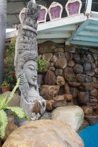 a statue sitting next to a stone wall at Momento Resort in Pattaya South