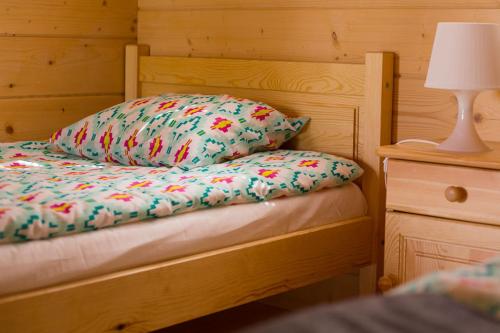 a bed with a pillow and a lamp on a night stand at Domki Drewniane Przystań Kajaczek in Białobrzegi