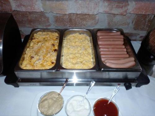 three trays of hot dogs and other food on a grill at Guest House Romantika Panzio in Gyula