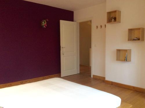 a bedroom with a purple wall and a white door at La villa des Savoyards in Vielsalm