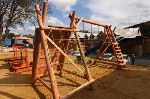 a wooden playground with a swing set in the dirt at Hotel Restaurant Svejk in Bublava