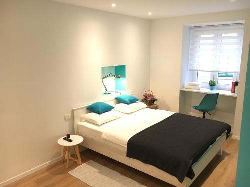 sypialnia z łóżkiem z niebieskimi poduszkami i oknem w obiekcie Adria w mieście Rijeka