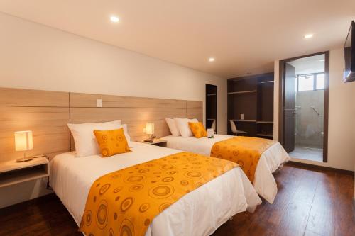 Dos camas en una habitación de hotel con amarillo y blanco en Hotel Plaza Carnaval, en Pasto