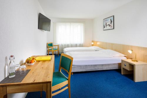 a hotel room with a bed and a table and a desk at Central Hotel Post in Chur