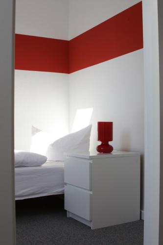 a bedroom with a white bed and a red accent wall at Lindenhotel Stralsund in Stralsund
