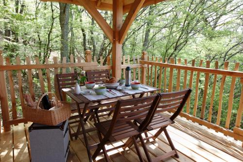 a wooden table and chairs on a wooden deck at Les Cabanes des Benauges in Arbis