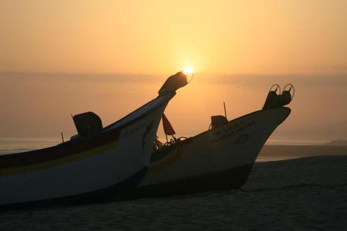 two boats sitting on the beach at sunset at Beach & Relax - Studio in Costa da Caparica